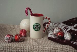 White and red ceramic mug with a red candy cane inside on a light background.