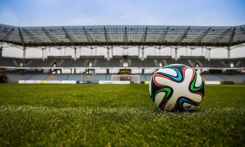 Soccer ball on green field in a large stadium under daylight