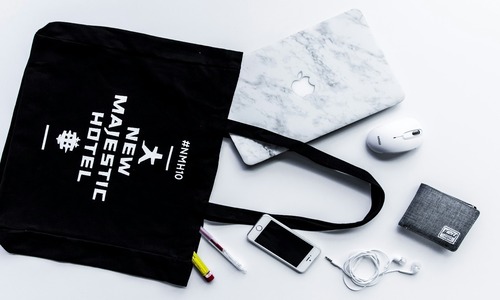 Flat lay tote bag with phone and wallet, showcasing branded promotional product design