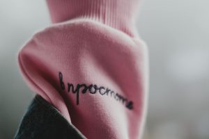 Close-up of pink fabric with cursive black embroidery, partially draped over denim.