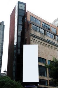 Large vertical blank billboard on a brick building, illustrating custom banner sizes.