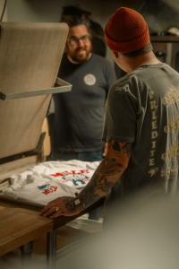 Two men chatting at a screen printing setup, encouraging meaningful guest engagement