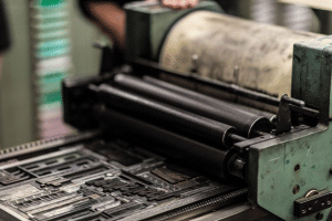 Close-up of a vintage letterpress printing machine with black ink rollers and metal type