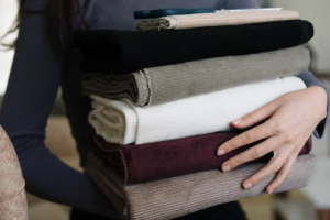Person holding a stack of neatly folded corduroy fabric bolts and textiles.