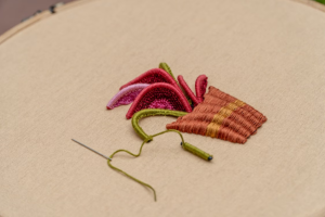 3D raised embroidery showing a potted plant design stitched onto fabric in a hoop.